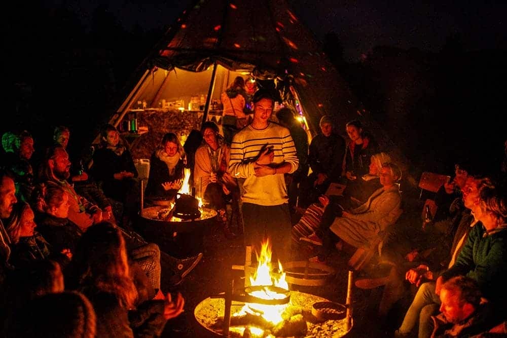Mensen bij kampvuur en tipi tent